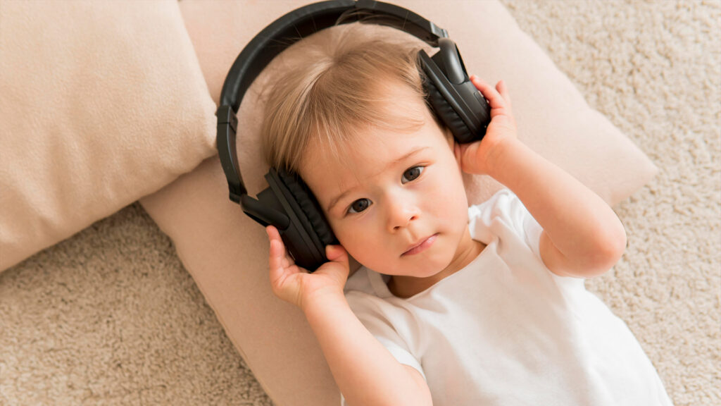 Un bambino sdraiato sul letto con delle cuffie per ascoltare musica sulle orecchie